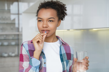 African american girl is taking medicine drug. Disease prevention, contraceptive pills taking.