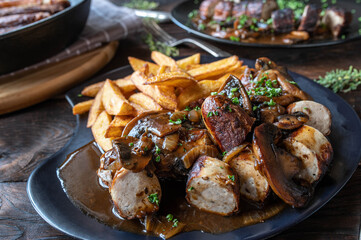 Bratwurst with brown onion, mushroom sauce and homemade french fries on wooden table. 