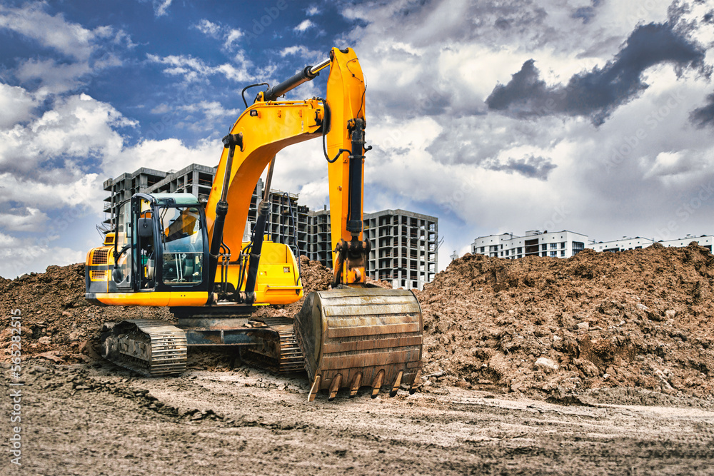 Wall mural a large yellow excavator moving stone or soil in a quarry. heavy construction hydraulic equipment. e