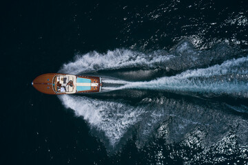 luxury wooden big motorboat with people fast moving on dark water top view - obrazy, fototapety, plakaty