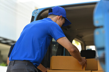 Shot of delivery men unloading cardboard boxes from cargo van. Delivery service, delivery home and shipping concept