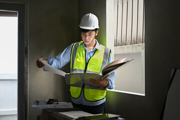 Architect man in reflective jackets working with blueprint, inspecting building construction site