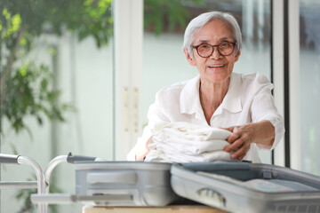 Happy smiling asian senior woman folding clothes in suitcase,preparation for journey,Retired old elderly packing luggage for trip,travel holiday vacation,life after retirement and lifestyle concept