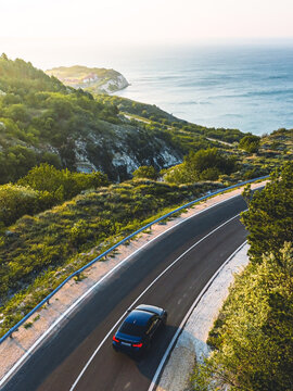 Driving on a coast road. Aerial view of a car driven on an amazing curved waving road at the Sea shore in Balchik sea resort in Bulgaria.