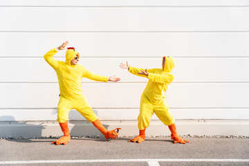 Carefree friends wearing chicken costumes gesturing and having fun