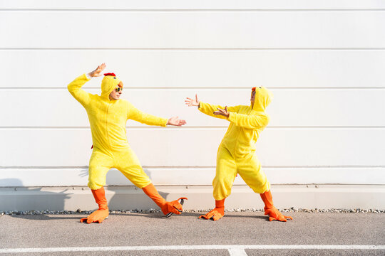 Carefree friends wearing chicken costumes gesturing and having fun