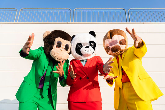 Woman with friends wearing masks gesturing in front of wall