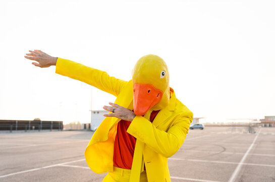 Man wearing yellow duck mask dancing in parking lot