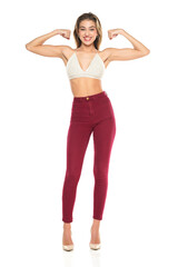 a young woman smiling in burgundy jeans and top, and high heels shoes showng biceps on a white background. Front view