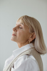 Studio portrait of a dreamy gray-haired senior woman. © dsheremeta