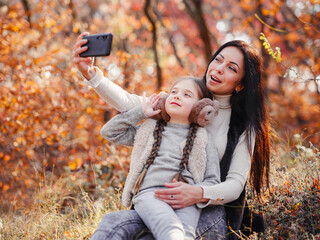 Fashionable mother with daughter. Family in a autumn park. - 565286707