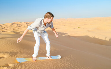 Young men sand surfing at the sand dunes of Dubai United Arab Emirates