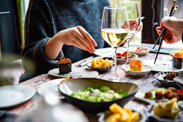 woman hand eating food in restaurant. wine, cheese, meat, vegetables and other appetizers on table