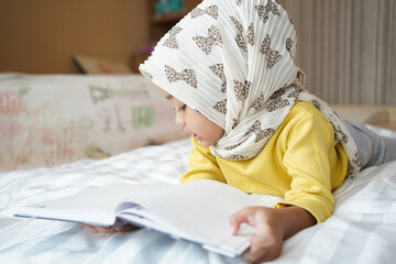 Asian Muslim little student is reading the book to at home. Education concept.