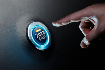 Hand of human going to press on start engine car button on black leather, happy new year 2023 start...