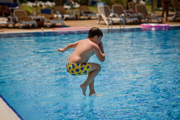 Naklejka premium Little boy is jumping in the swimming pool.