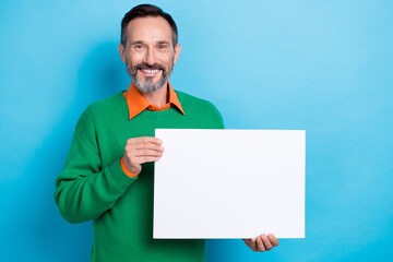 Photo of middle age brunet hair entrepreneur hold paper banner empty space advertising new brand cheap proposition isolated on blue color background