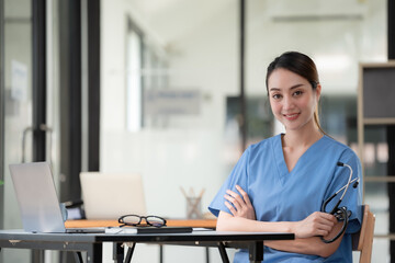 Obraz premium Smiling adult woman doctor in a blue uniform stethoscope with folded arms, a confident female medic looking at the camera.