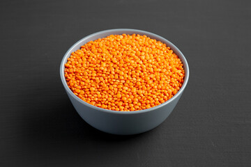 Red Lentils Legume in a Bowl on a black surface, side view.
