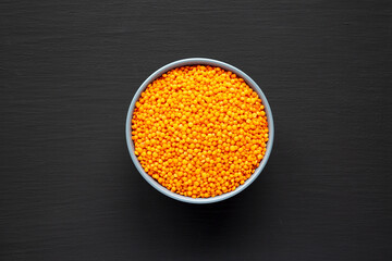Red Lentils Legume in a Bowl on a black background, top view. Flat lay, overhead, from above.