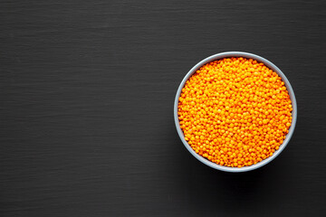 Red Lentils Legume in a Bowl on a black background, top view. Flat lay, overhead, from above. Copy space.
