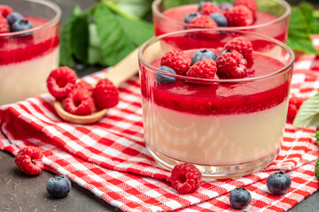Raspberry Panna cotta with raspberry jelly on a dark background. Berry dessert with cream sauce in...