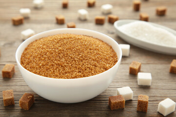 White and brown sugar in bowl on grey background. Vertical photo