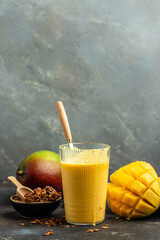 Healthy mango smoothie in a glass. Indian healthy ayurvedic cold drink with mango, Delicious breakfast or snack, vertical image. place for text