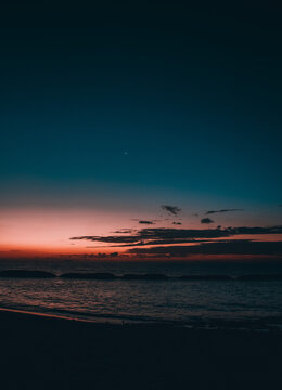 Amanecer cerca de la costa con la luna de fondo