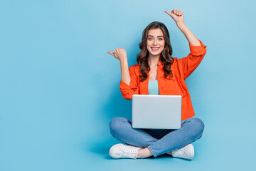 Full size photo of pretty girl point empty space laptop apple macbook samsung dressed stylish orange look isolated on blue color background