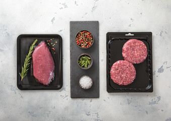 Raw fresh beef sirloin fillet steak and mince burgers sealed in vacuum tray on light kitchen...