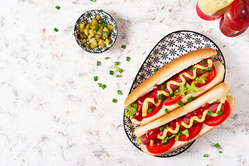 Hot dog with grilled sausage, tomato and lettuce on light background. American hot dog. Top view,...