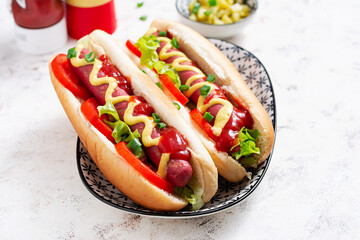 Hot dog with grilled sausage, tomato and lettuce on light background. American hot dog.