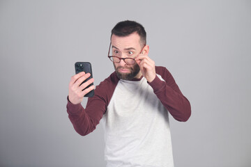Young man looking at a strange news item while lowering his glasses to see better - 565302912
