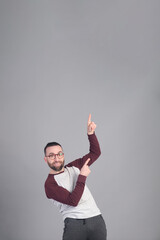 Young man standing pointing upward to a large copy space in studio shot - 565302918