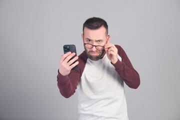 Young man looking at strange news while lowering his glasses to see better - 565302930
