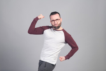 Young man flexing his arms in funny way in a studio shot - 565302990