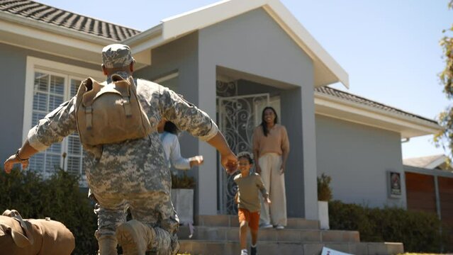 Mom And Two Kids Welcome Dad Home With A Military Homecoming Sign, And Then With A Warm Family Hug. Excited And Joyful, This Military Family Reunites With The Father After A Long Deployment In The Arm