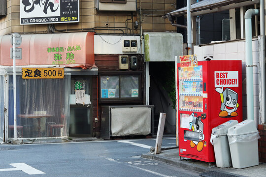 TOKYO, JAPAN - January 24, 2023: A street in Tokyo's Shinjuku Ward with a restaurant and a drinks vending machine in front of an apartment building.