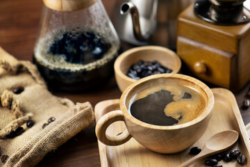 Coffee cup and coffee beans on table . Drip coffee made by spills hot water from teapot to Finely ground coffee on paper filter
