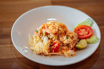 A plate of fried rice is on the table. A dish of fried rice with seafood and vegetables with the addition of an egg. Asian dish. 