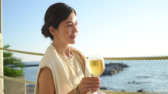 海辺のレストランでビールを飲む美しい大人の女性