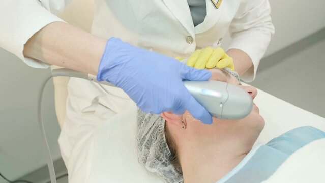 Professional face skin rejuvenation, lifting procedure. Cosmetologist uses modern ultrasound device. Hardware cosmetology