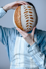 Sourdough bread Scoring pattern. A woman covering her face with freshly baked bread. Art food