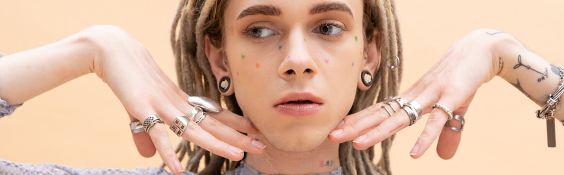 Nonbinary person with dreadlocks and rings on fingers isolated on yellow, banner.