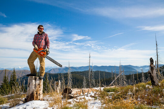 Man Standing With Chainsaw On Tree Stump While Camping In Montana