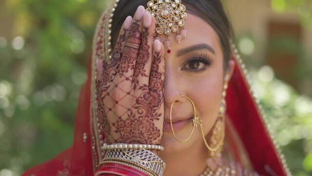 Portrait of a happy Indian bride covering her face with her hand, Hindi on her hand