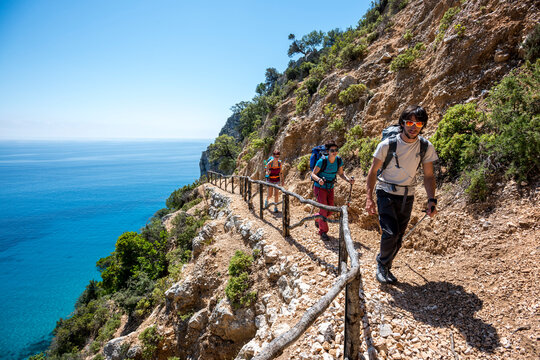 A boy and two girls hiking in Pedra Longa, Sardinia, Italy.