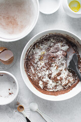 Loosely folded chocolate cake batter in a white bowl, chocolate madeleines batter being mixed