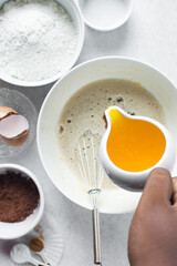 Pouring melted butter into a white mixing bowl